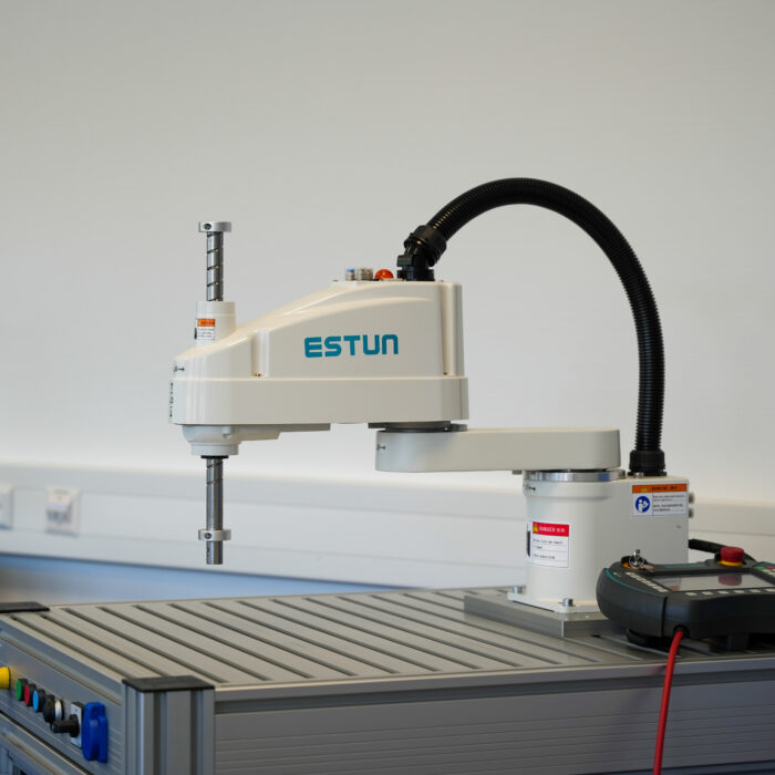 Ein weißer ESTUN-Roboterarm ist auf einem Metalltisch in einer Laborumgebung montiert, daneben befinden sich Kabel und ein Steuergerät.